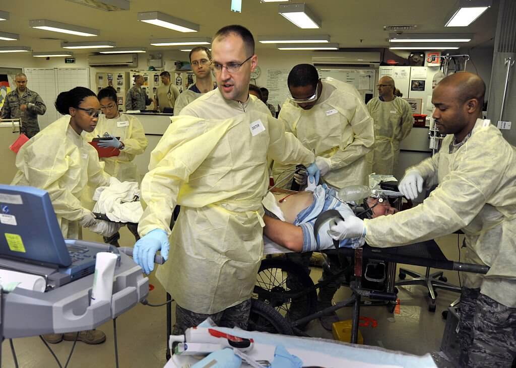 Medical personnel simulate emergency treatment during a mass casualty exercise at Balad's Air Force Theater Hospital. Credit https://commons.wikimedia.org/wiki/File:Emergency_medicine_simulation_training_exercise_in_Balad,_Iraq.jpg
